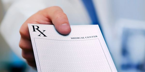 Doctor holding out a blank prescription pad.