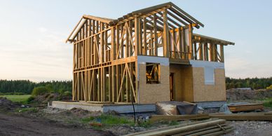 Wooden frame of a house under construction at dusk in a rural area.
