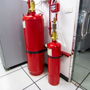 Two red fire suppression cylinders mounted on a wall.