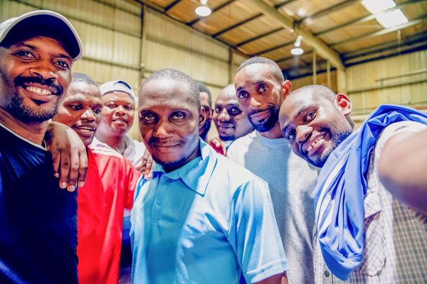 Group enjoying a meal with orange soda at a long table.