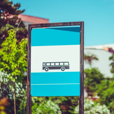 A blue and white bus stop sign with a bus icon outdoors.