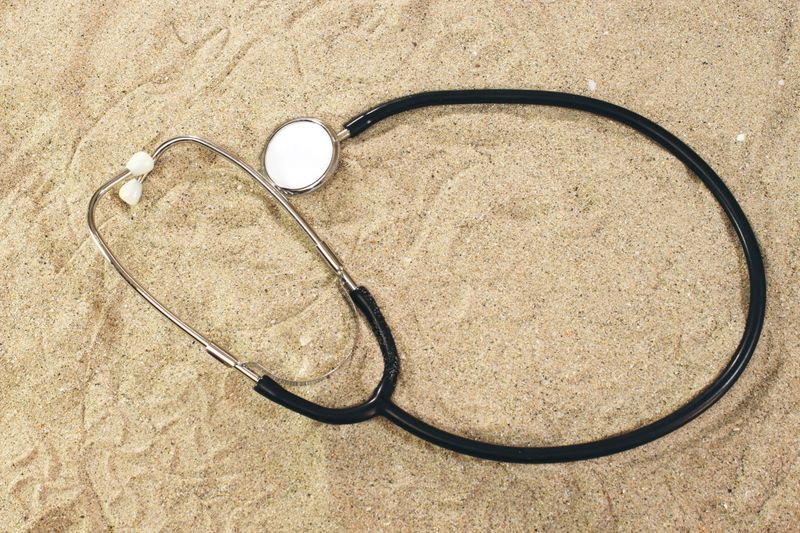 Stethoscope in sand, summer concept
