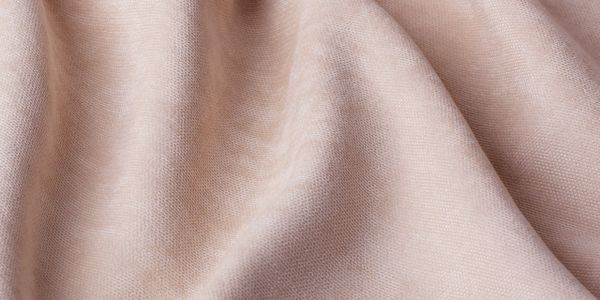 Close-up of soft, pale pink fabric with gentle folds.
