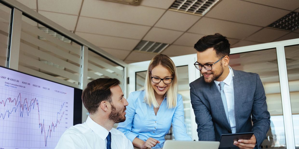 Three colleagues discuss business strategy with a laptop and charts.
