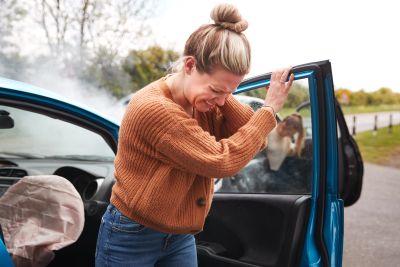 Woman reacting to airbags deployed in a car crash.
