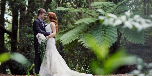 Bride and groom embracing in a forest.