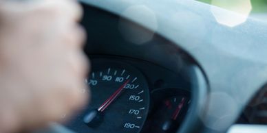 Close-up of a car speedometer showing speed around 130 km/h.