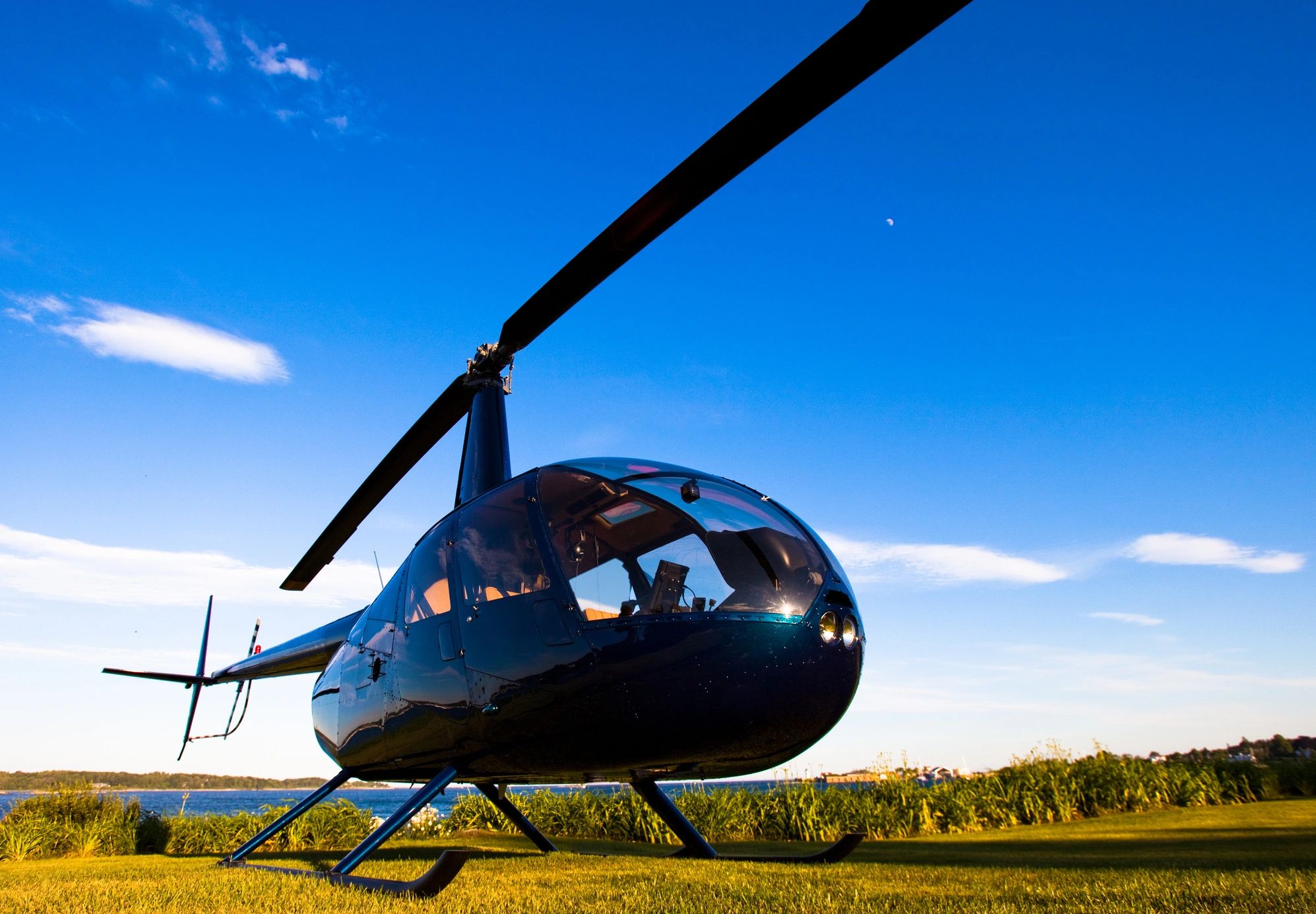 A helicopter on grass under a clear blue sky.