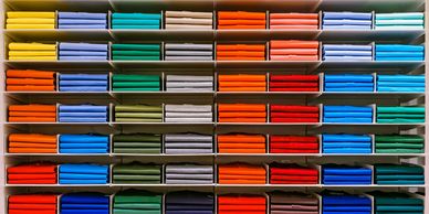 Colorful folded fabrics neatly arranged on shelves in rows.