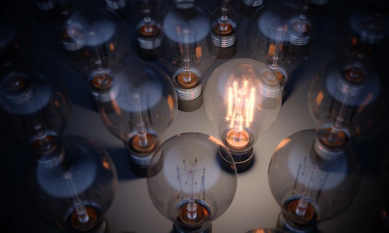 Glowing Light Bulb between the others. Can be used leadership, innovation and individuality concepts.  (3d render)