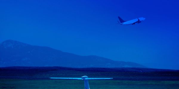 An airplane takes off against a mountainous backdrop during twilight.