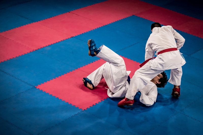 Photo of a male karate practitioner punching his sparring partner while he is on the ground.