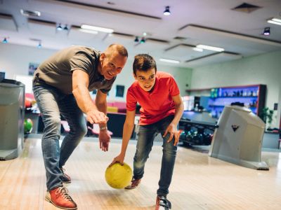 Man and boy bowling and smiling.