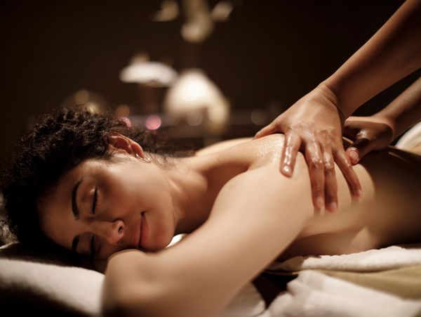 A woman enjoys a relaxing back massage in a dimly lit room.