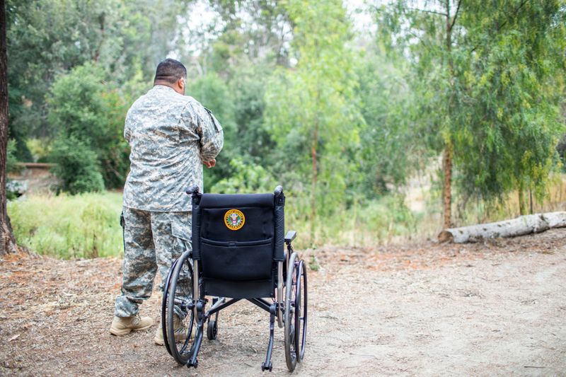 A veteran stands next to his wheelchair