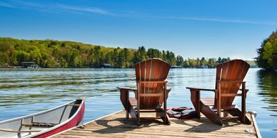 Sunny day with a dock and chair on a lake.