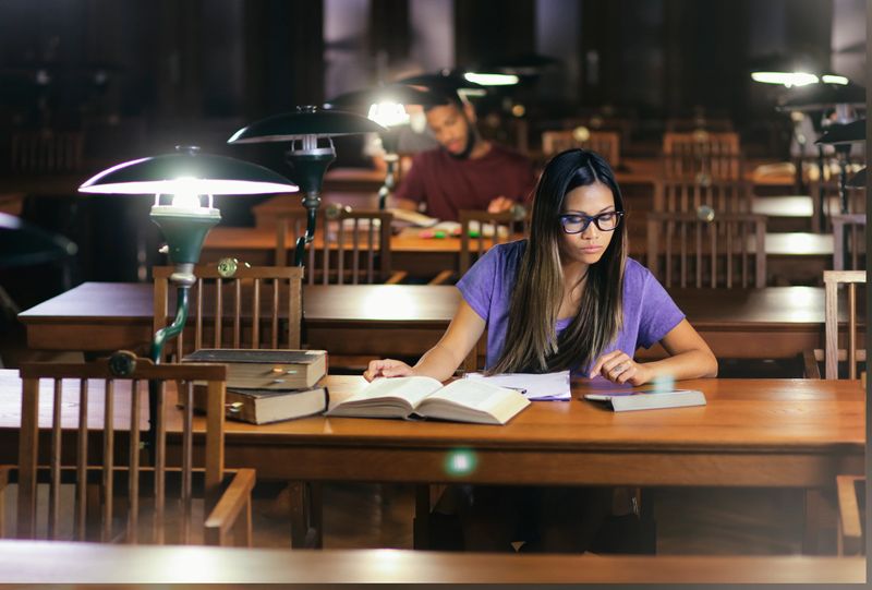Young vietnamesse woman  studying in a library reading room in the evening.