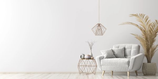 Minimalist living room with white armchair, geometric side table, and dried plants.