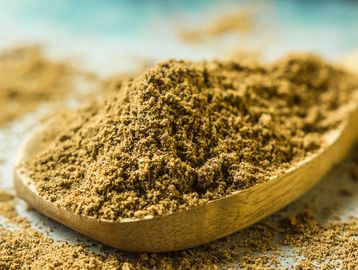 Close-up of a wooden spoon with ground spice powder.