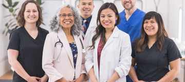 Smiling female dentist with a child patient and male dentist in the background.