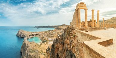 Ancient Greek temple ruins overlooking a coastal cliff and blue sea.