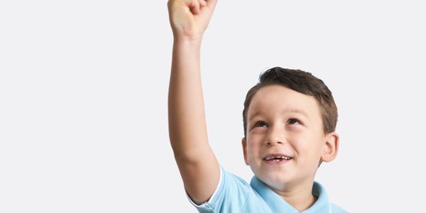 Happy boy reaching upward with a smile.