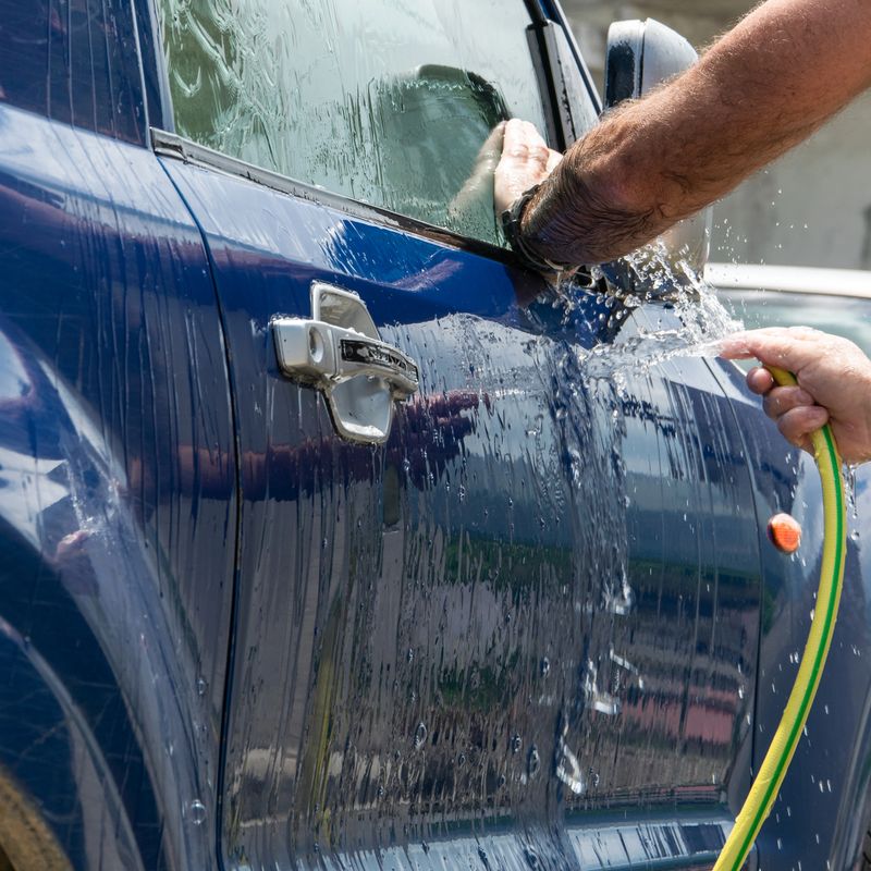 Close up view of man hands washing automobile.