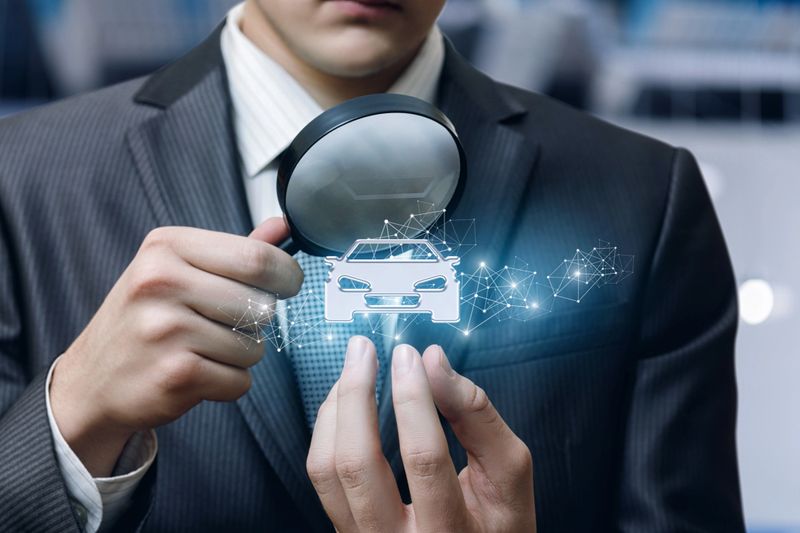 The concept of inspection and examination of the car . Businessman looking at a car through a magnifying glass.