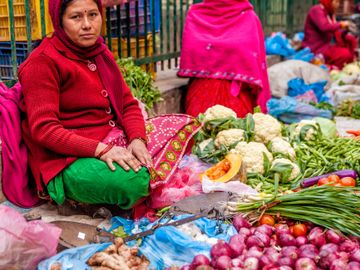 A woman selling fresh vegetables at an outdoor market.