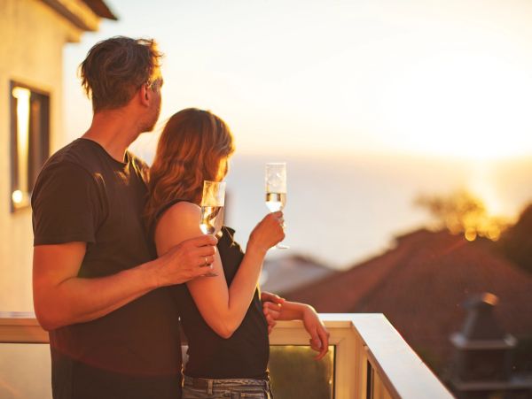 Couple enjoying sunset with drinks on terrace.