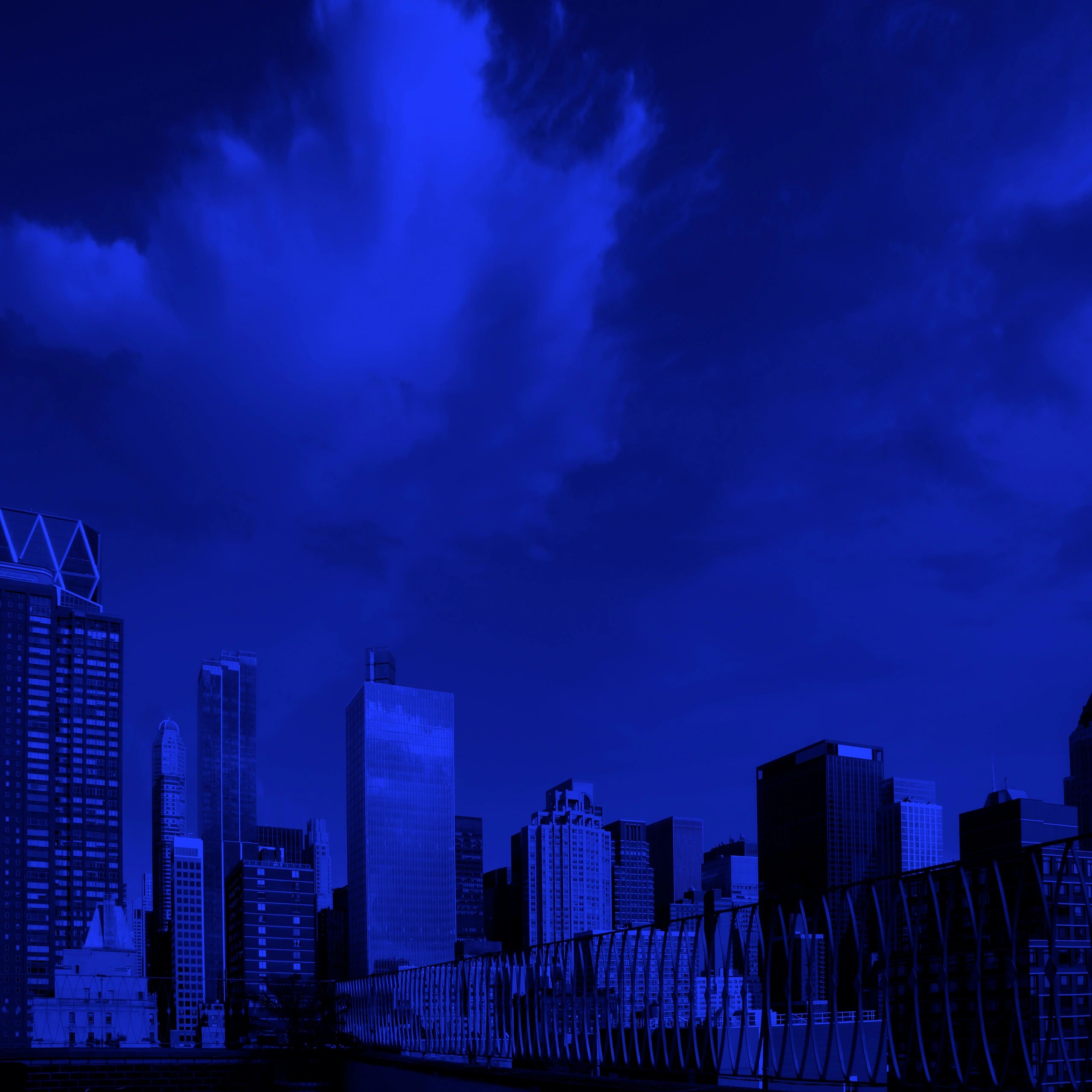 City skyline at dusk with dramatic clouds and a blue overlay.