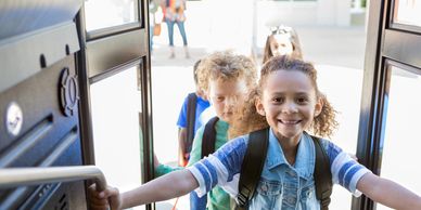 Happy children boarding a school bus, ready for a day of learning.