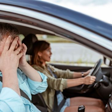 Man stressed while woman drives a car.