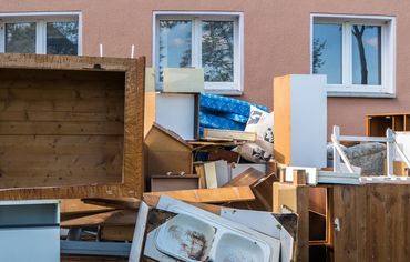Discarded old furniture and household items piled outside a building. dumpster rental waste removal junk removal NorthWestern North Western rental house eviction 