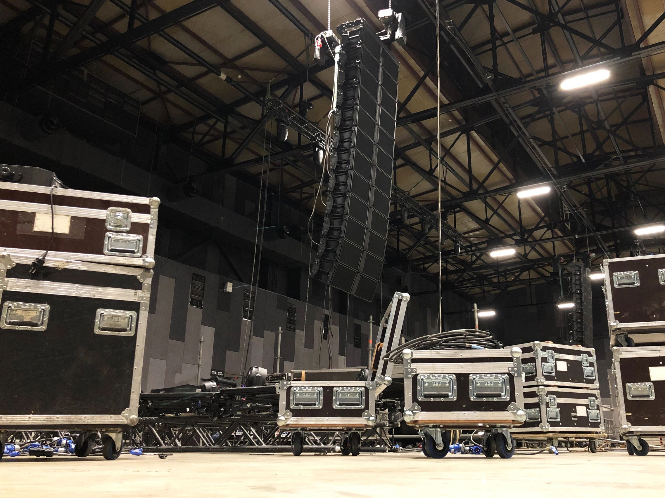 Large speakers and equipment cases in an indoor event space.