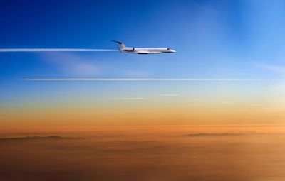 Private jet flying above the clouds at sunset.