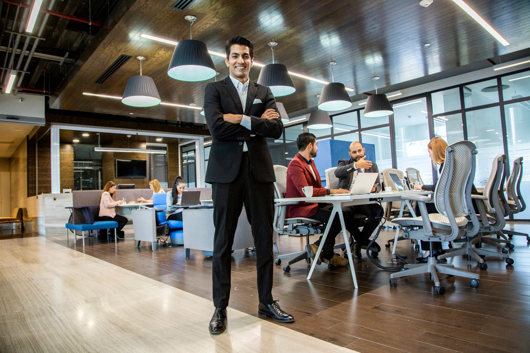 Confident businessman in office with colleagues working in modern workspace.