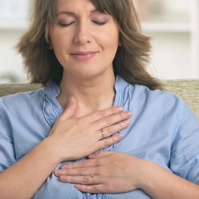 A woman meditating with her hands on her chest and her eyes closed.