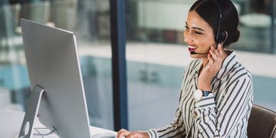 Woman wearing headset working at computer in modern office.