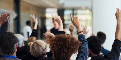 People raising hands in a group setting.