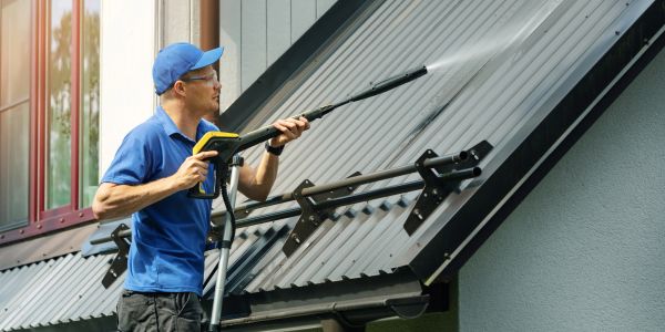 Man pressure washing a roof.
