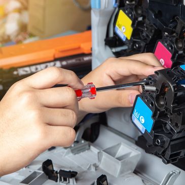 Person repairing a printer with a screwdriver, focusing on the toner cartridge.