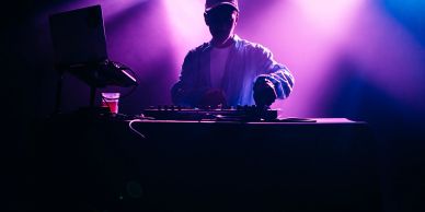 DJ performing with purple lighting.