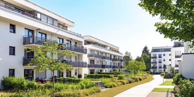 Modern residential buildings with balconies and greenery.