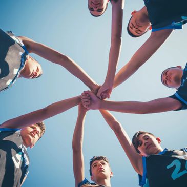 A group of young basketball players huddling with hands together in unity.