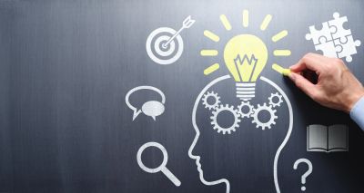 Hand drawing a bright idea and problem-solving concepts on a chalkboard.