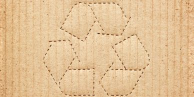 Recycling symbol outlined on cardboard surface.