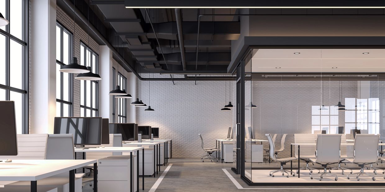 Modern open office space with white desks and glass meeting room.