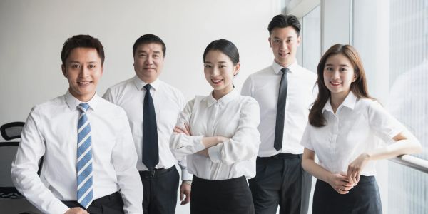 Group of five professionals posing in office.