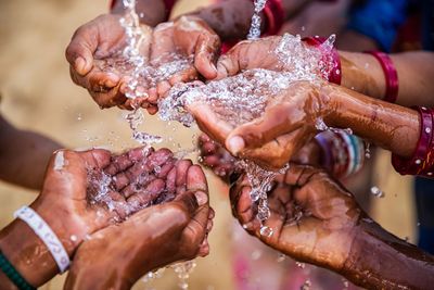 Multiple hands catching flowing water, symbolizing unity and life.